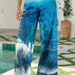 Pantaloni larghi da donna con stampa blu e bianca, indossati con sandali bianchi, in un ambiente estivo vicino a una piscina. Design elegante e fresco, ideale per look casual e vacanze.