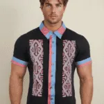 Modello maschile che indossa una camicia a maniche corte con un design colorato e moderno, caratterizzata da motivi geometrici e dettagli in blu e rosa.