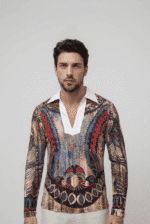 Uomo che indossa una camicia a maniche lunghe con un design artistico e dettagli colorati, in un contesto neutro.