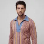 Uomo in camicia a righe colorate con colletto blu, in posa su sfondo neutro. Stile moderno e alla moda.