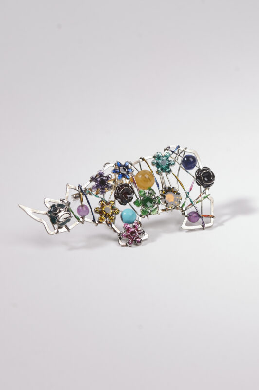Gioiello artigianale in argento a forma di animale decorato con pietre colorate e fiori, ideale per accessori unici e originali.