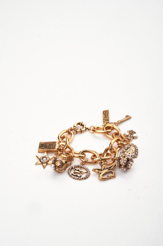 Braccialetto in oro con charm vari, tra cui simboli e figure decorative, su sfondo bianco.