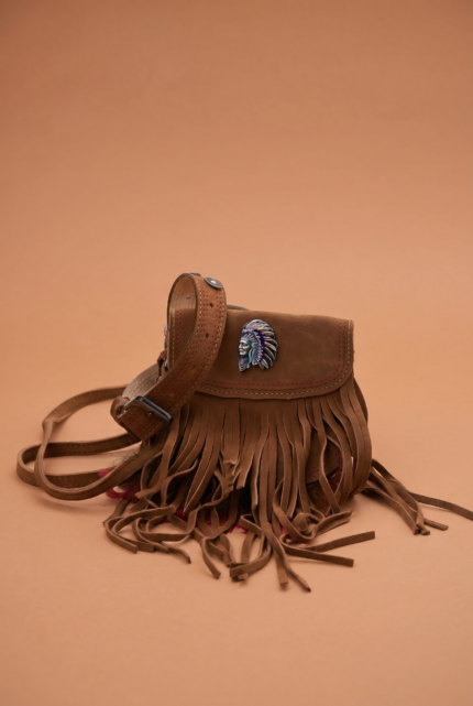 Borsa in pelle scamosciata marrone con frange e decorazione a forma di capo indiano, su sfondo colorato. Ideale per uno stile bohemien e casual.