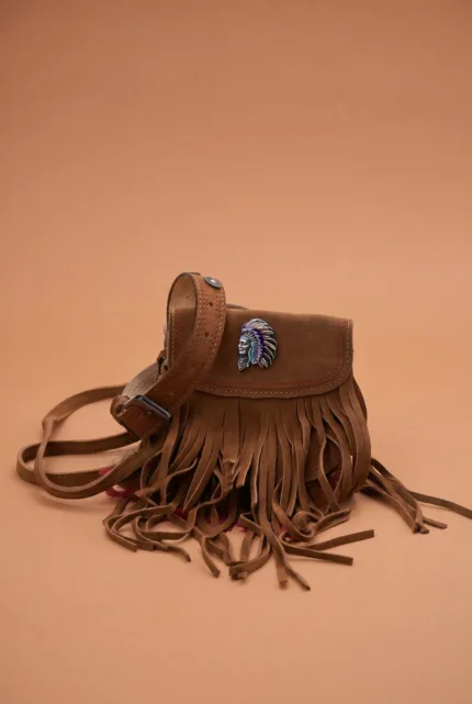 Borsa in pelle scamosciata marrone con frange e decorazione a forma di capo indiano, su sfondo colorato. Ideale per uno stile bohemien e casual.