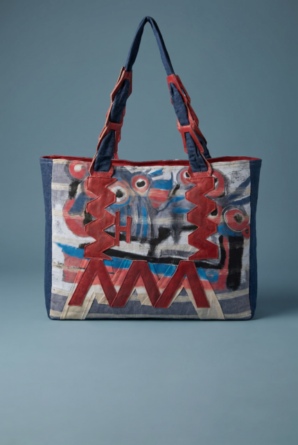 Borsa a spalla colorata con motivi artistici, caratterizzata da manici rossi e dettagli in tessuto blu e bianco, ideale per un look moderno e creativo.