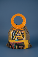 Borsa di design con manico circolare arancione e motivo artistico su sfondo giallo e nero, su un supporto blu. Ideale per uno stile contemporaneo e creativo.