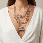 Collana multistrato colorata indossata da una donna, con perline di diversi colori e un pendente a forma di coniglio fiorito, su sfondo neutro e abbigliamento bianco.