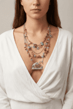 Collana multistrato colorata indossata da una donna, con perline di diversi colori e un pendente a forma di coniglio fiorito, su sfondo neutro e abbigliamento bianco.