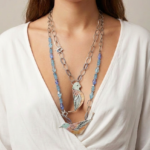 Collana elegante con pendenti a forma di uccelli, realizzata in argento e perline blu, indossata da una donna con una maglietta bianca. Perfetta per aggiungere un tocco di stile a qualsiasi outfit.