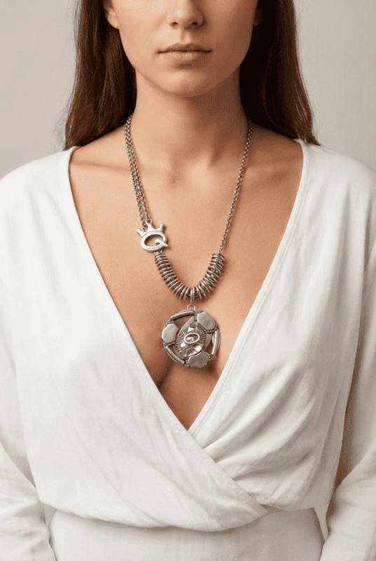 Collana in argento indossata da una donna con scollatura a V, caratterizzata da un pendente decorativo a forma di occhio e una catena con spirali.