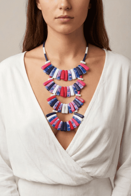 Collana moderna e colorata indossata da una donna, composta da pezzi in blu, rosa e rosso, su sfondo neutro. Perfetta per aggiungere un tocco di stile a qualsiasi outfit.