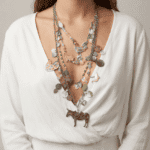 Collana multistrato indossata da una donna, composta da pendenti colorati a forma di animali e perle decorative, abbinata a una camicia bianca.
