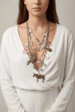 Collana multistrato indossata da una donna, composta da pendenti colorati a forma di animali e perle decorative, abbinata a una camicia bianca.
