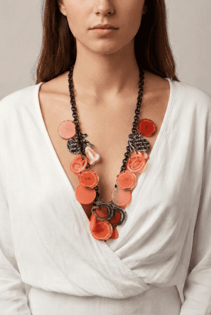 Collana colorata con dettagli floreali e geometrici, indossata da una donna con abbigliamento bianco, perfetta per aggiungere un tocco di stile a qualsiasi outfit.