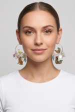 Modella con orecchini a cerchio decorati con animali e fiori, indossando una maglietta bianca. Gli orecchini presentano un design colorato e creativo, evidenziando dettagli come un'anatra e un coniglio.