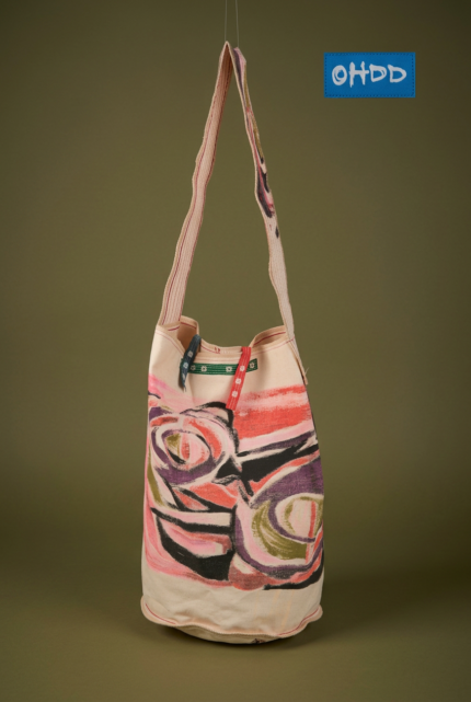 Borsa a tracolla con design artistico, realizzata in tessuto leggero, con motivi colorati e manici a strisce. Ideale per un look casual e moderno.