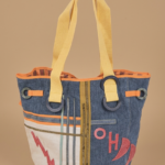 Borsa a spalla in denim con manici gialli, decorata con motivi grafici colorati, ideale per un look casual e alla moda.