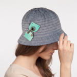 Cappello cloche in cotone effetto denim con dettagli decorativi, indossato da una donna con capelli lunghi, in un contesto neutro.
