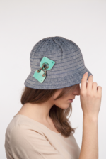 Cappello cloche in cotone effetto denim con dettagli decorativi, indossato da una donna con capelli lunghi, in un contesto neutro.