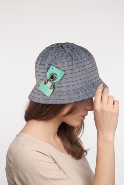 Cappello cloche in cotone effetto denim con dettagli decorativi, indossato da una donna con capelli lunghi, in un contesto neutro.