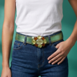 Cintura in vera pelle verde con maxi fibbia decorata da pietre sintetiche, indossata da una donna in t-shirt bianca e jeans.