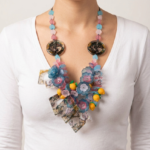 Collana in PVC ispirata a Positano, caratterizzata da fiori colorati, elementi in plastica e dettagli vivaci, indossata da una donna in maglietta bianca.