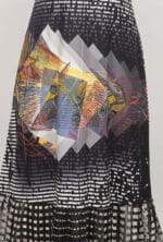 Long skirt with geometric patterns and bright colors, featuring an abstract design with shades of black, white, red, yellow and blue. Ideal for a modern and creative look.