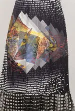 Gonna lunga con motivi geometrici e colori vivaci, che presenta un design astratto con sfumature di nero, bianco, rosso, giallo e blu. Ideale per un look moderno e creativo.