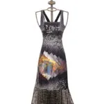 Abito lungo con stampa grafica multicolore, presentato su un manichino elegante. Il design include motivi geometrici e una combinazione di colori vivaci, ideale per occasioni estive.