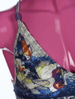 Dettaglio di un top estivo con stampa colorata di pesci e con spalline regolabili, esposto su un manichino rosa. Ideale per la moda estiva e per outfit da spiaggia.