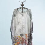 Elegant and lightweight cape with floral and fruity motifs displayed on a metal mannequin. Ideal for summer outfits and special occasions. 