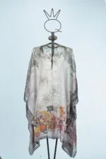 Cappa elegante e leggera con motivi floreali e fruttati, esposta su un manichino in metallo. Ideale per outfit estivi e occasioni speciali.