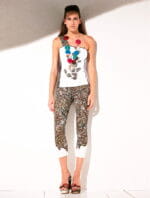 Model in summer attire, wearing a white embellished top and geometric patterned leggings. Colorful necklace and elegant sandals complete the look. Neutral background.
