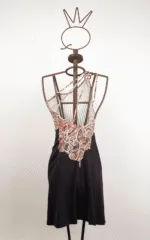 Abito estivo con spalline incrociate, caratterizzato da un design a motivi geometrici e una gonna nera, esposto su un manichino di metallo.