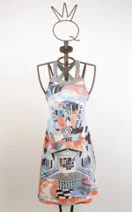 Abito estivo colorato con stampa geometrica e motivi artistici, presentato su un manichino. Ideale per occasioni casual e vacanze, con spalline incrociate e dettagli vivaci.