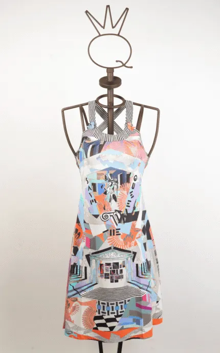 Abito estivo colorato con stampa geometrica e motivi artistici, presentato su un manichino. Ideale per occasioni casual e vacanze, con spalline incrociate e dettagli vivaci.