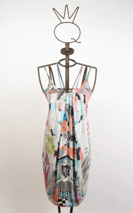 Abito estivo multicolore con spalline, esposto su un manichino. Il design presenta una combinazione di motivi geometrici e floreali, perfetto per occasioni informali e calde giornate estive.
