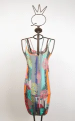 Abito colorato con spalline sottili appeso a una gruccia, caratterizzato da un design vivace con motivi floreali e linee geometriche, ideale per la stagione estiva.