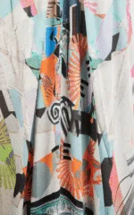 Dettaglio di un tessuto colorato con motivi astratti, caratterizzato da tonalità vivaci come arancione, blu e verde, ideale per abbigliamento estivo o moda contemporanea.