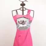 Abito rosa con spallina unica e stampa grafica, esposto su un manichino con supporto a forma di corona. Perfetto per look estivi e casual.