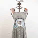 Abito estivo a righe bianche e nere con dettagli colorati, esposto su una gruccia artistica a forma di corona, ideale per look casual e alla moda.