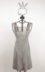 Abito a righe bianche e nere su manichino, con spalline colorate. Design elegante e moderno, ideale per occasioni estive.