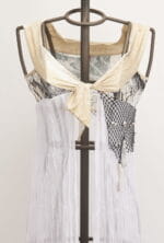 Top in tessuto leggero con dettagli in rete nera e drappeggio bianco, esposto su un manichino. Design moderno e creativo, ideale per look estivi e casual.