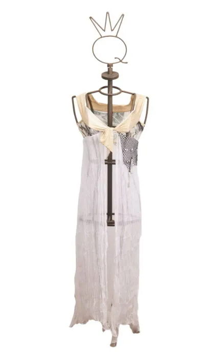 Abito lungo su manichino, realizzato in tessuto leggero e trasparente, con dettagli in colori chiari e decorazioni artistiche. Perfetto per occasioni estive e look casual.