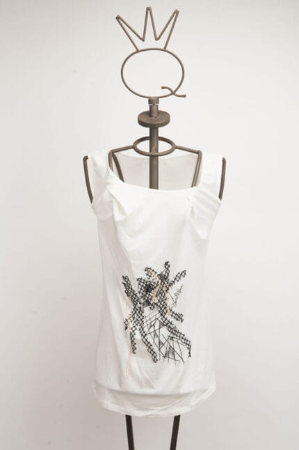 Top bianco con dettagli grafici neri, presentato su un manichino con testa a forma di corona. Ideale per un look casual e alla moda.