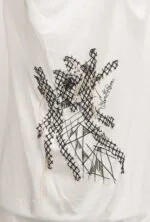 Maglietta bianca con ricamo nero artistico, caratterizzata da un design astratto e dettagli in corda. Ideale per uno stile casual e creativo.