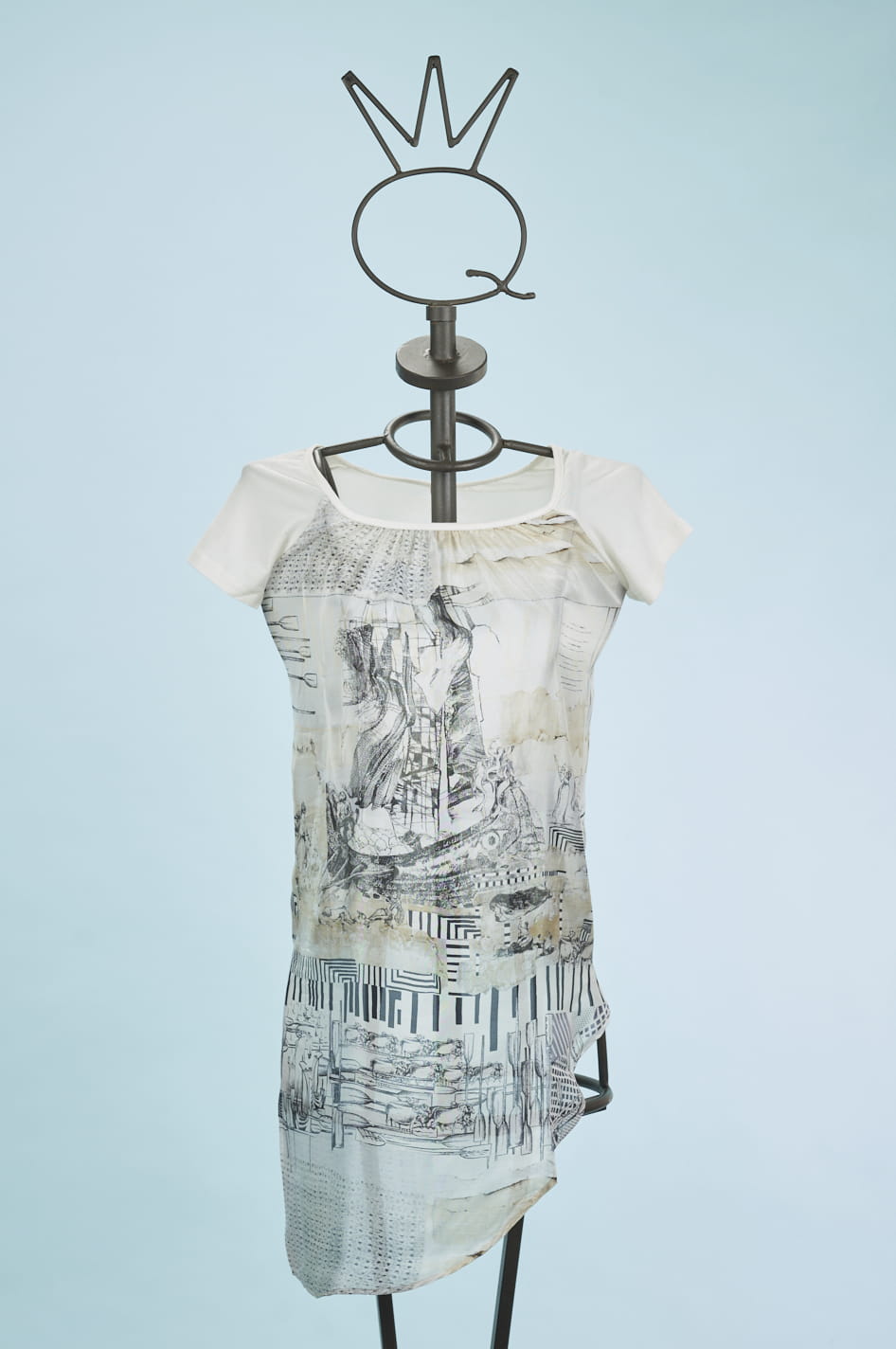 13SSNA624_a Abito femminile con maniche corte, caratterizzato da un design artistico in bianco e nero su fondo chiaro. Indossato su un manichino con un supporto a forma di corona, il vestito presenta dettagli grafici e un taglio asimmetrico, ideale per look casual e creativi. Sfondo azzurro che mette in risalto il capo.