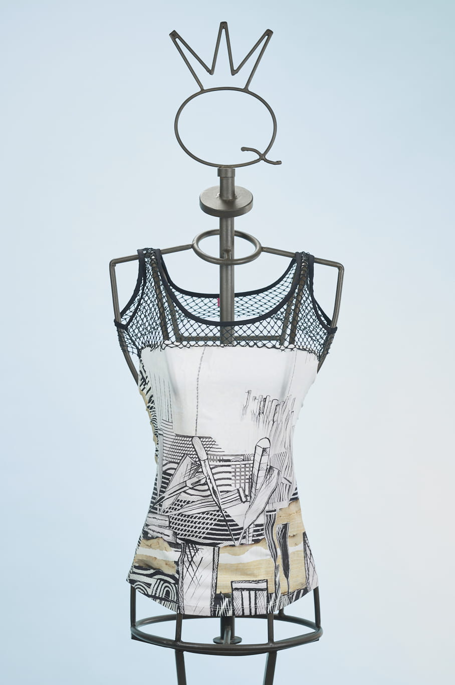 13SSNA625_a Top in tessuto con stampa artistica su manichino, caratterizzato da spalline in rete nera e design moderno. Sfondo azzurro chiaro.