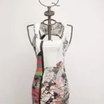 Abito estivo a maniche corte con un design astratto multicolore, esposto su un manichino. Il vestito presenta motivi geometrici e floreali, ideale per occasioni casual e di moda.