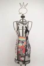 Abito femminile con stampe colorate su manichino, caratterizzato da un design moderno e artistico, con dettagli in bianco e nero e colori vivaci. Ideale per occasioni casual o eventi estivi.